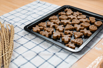 Young male baking cookies in kitchen at home. Male making Christmas cookies in many shape on a wooden board. Young man cooking cookies in kitchen. Making homemade shortbread cookies. 