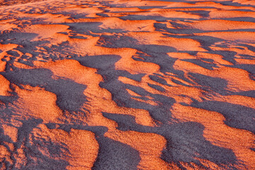 Harmonious lines of sand in the desert at sunrise; bizarre wind patterns in the soft light of the rising sun