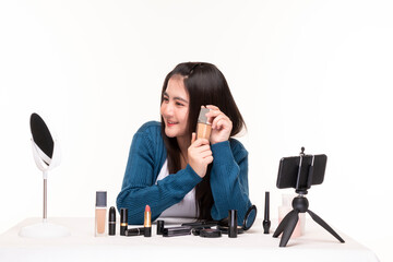 Obraz premium Young female makeup artist doing video blog about cosmetics. Beauty female beauty vlogger bloggers doing a cosmetic makeup tutorial review of cosmetic products. Pretty woman doing makeup at home. 