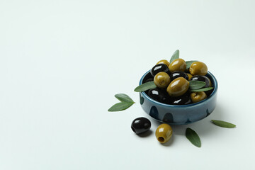 Bowl of olives and leaves on white background