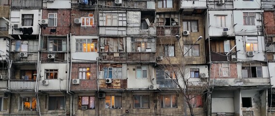Old windows and balconies. Facade of a dilapidated house of post-Soviet architecture
