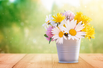 wildflowers in a metal bucket on a wooden table