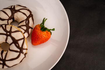 donuts and fresh strawberries on black background