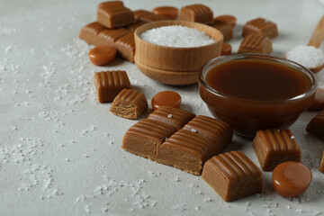 Concept of sweet food with caramel pieces, salt and caramel sauce on white textured background