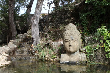 Fototapeta na wymiar estatua de buda en pequeño lago y catarata