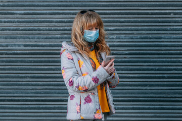 woman with mask on mobile phone in the street