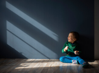 a little boy of three years old sits in the sunlight, a place for text, selective focus