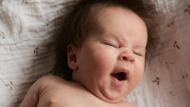 Cinematic video portrait new born baby yawns, sleepy cute baby child. Maternity and healthy sleep concept.