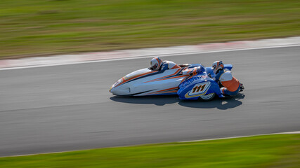 A panning shot of a racing sidecar as it corners on a track.