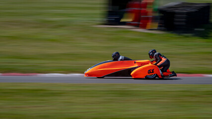A panning shot of a racing sidecar as it corners on a track.