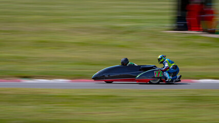 Obraz premium A panning shot of a racing sidecar as it corners on a track.