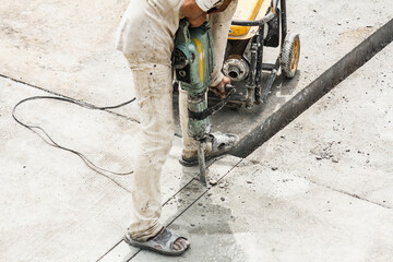 Construction worker using jackhammer drilling concrete surface