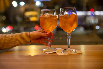 concept of evening time in bar. female hand holds coctail, and another coctail is on the table