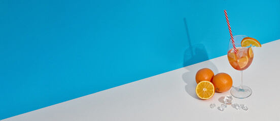 Fruit drink with ice and oranges on double white blue background with shadow. Cocktail. Orange juice