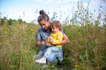 mom and daughter toddler collect a bouquet of wildflowers flowers yarrow close-up