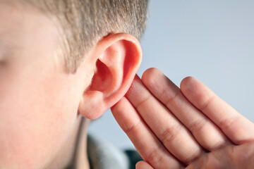 Boy with hand on ear listening for quiet sound or paying attention