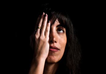 portrait of an attractive woman covering half of her face with her hand and looking upclosed eye