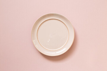Empty ceramic round plate isolated on pink background. top view