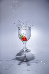 The strawberry falls into a glass of water
