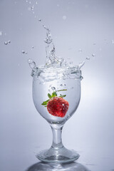 The strawberry falls into a glass of water
