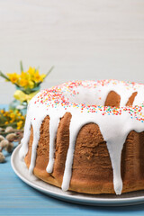 Glazed Easter cake with sprinkles on light blue wooden table, closeup
