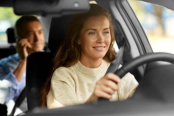 transportation, vehicle and people concept - happy smiling female driver driving car with male passenger calling on phone
