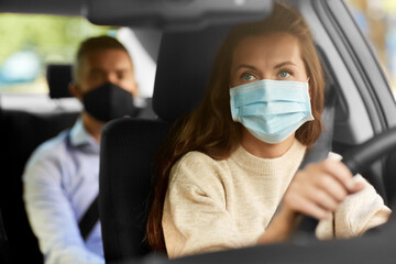 Fototapeta na wymiar transportation, health and people concept - female driver driving car with male passenger wearing face protective medical mask for protection from virus disease