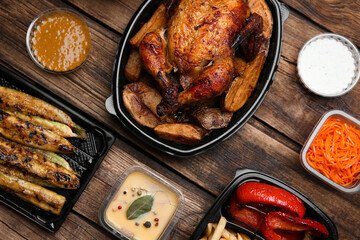 Plastic containers with different dishes on wooden table, flat lay. Food delivery service
