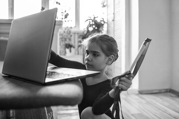 Pre teen girl in black sportswear watching world sport competition online and repeating exercises,...