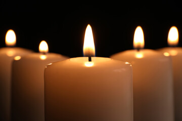 Burning candles on dark background, closeup. Memory day