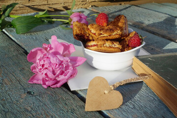 Shortbread, peony flower, strawberries and old book with heart bookmark