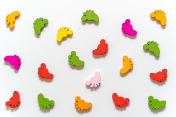 Multicolored wooden figurines in the form of children's feet on a white background. 