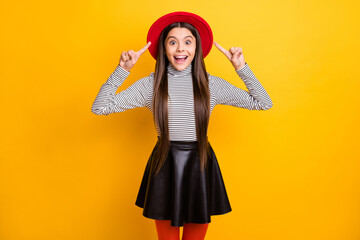 Portrait of attractive amazed cheerful long-haired girl demonstrating new cool hat isolated over bright yellow color background