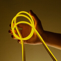 Flexible yellow led tape neon in hand on black background