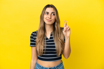 Young caucasian woman isolated on yellow background with fingers crossing and wishing the best