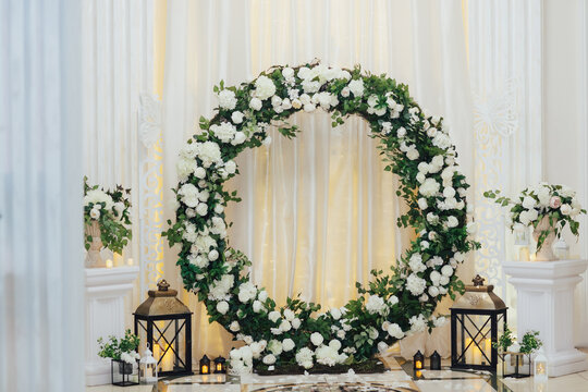 Beautiful wedding round arch decorated with flowers, greenery and candles in the luxury restaurant. Wedding ceremony. 