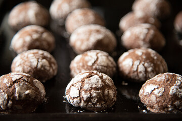 Cracked chocolate cookies with icing sugar on a pan