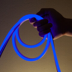 Flexible blue led tape neon in hand on black background