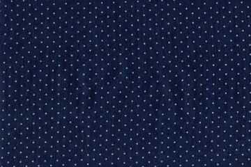 The texture of a natural blue denim fabric with small polka dots. Abstract cotton fabric background.
