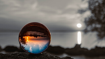Crystal ball alpine landscape shot with black and white background outside the sphere and reflections at the famous Chiemsee, Chieming, Bavaria, Germany