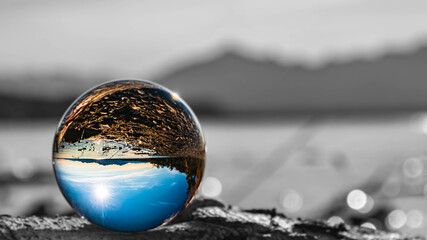 Crystal ball alpine landscape shot with black and white background outside the sphere and reflections at the famous Chiemsee, Chieming, Bavaria, Germany