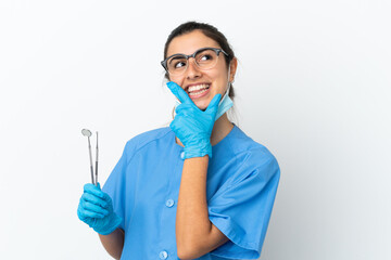 Young woman dentist holding tools isolated on white background happy and smiling