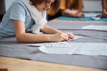 Obraz na płótnie Canvas Adorable girl preparing fabric in sewing workshop