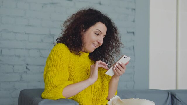 Cute smiling lady with curly hair smiling doing shopping online, making order