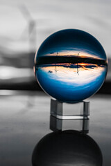 Crystal ball landscape shot with black and white background outside the sphere and reflections on a car roof and wind turbines near Kugl, Bavaria, Germany