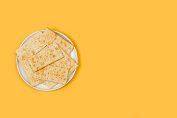 Galletas saladas sobre un plato redondo blanco sobre un fondo amarillo liso y aislado. Vista superior. Copy space