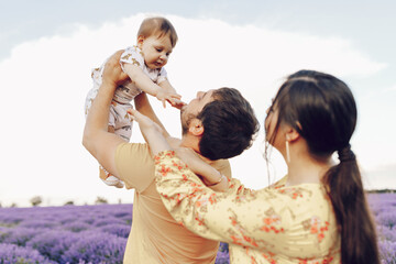 Dad and mom, parents play with their little son in a lavender field. Summer day.