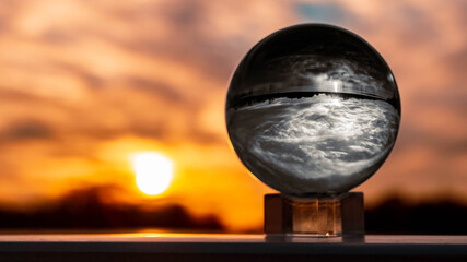 Crystal ball black and white sunset shot with colored background outside the sphere and reflections near Plattling, Isar, Bavaria, Germany