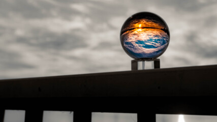 Crystal ball sunset landscape shot with black and white background outside the sphere and reflections near Plattling, Isar, Bavaria, Germany