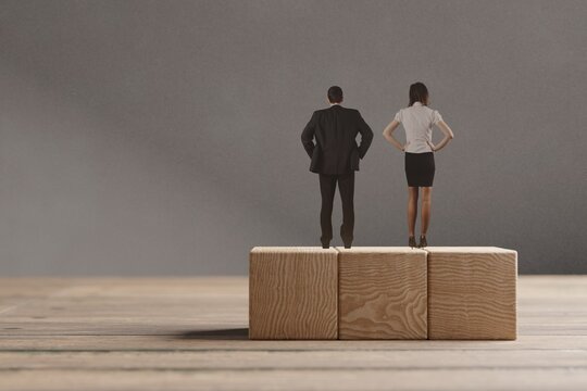 Miniature man and woman standing on the wooden blocks. The concept of equal opportunities for genders.